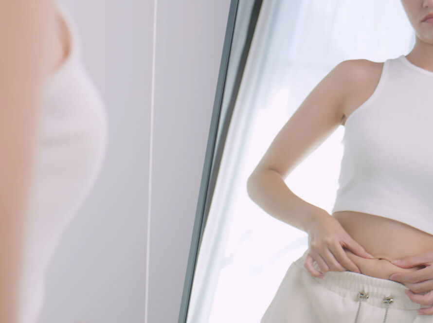 A young woman is worried about her body while looking in the mirror image