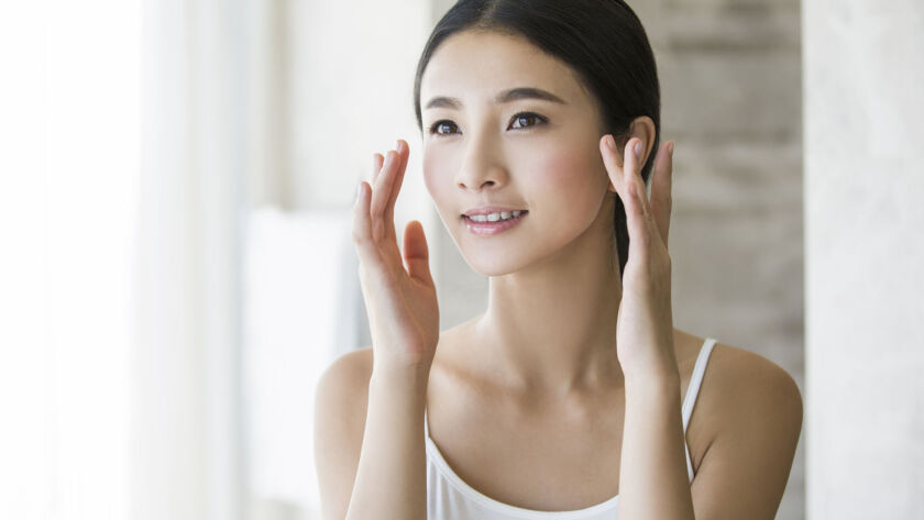 Young woman applying moisturizer image