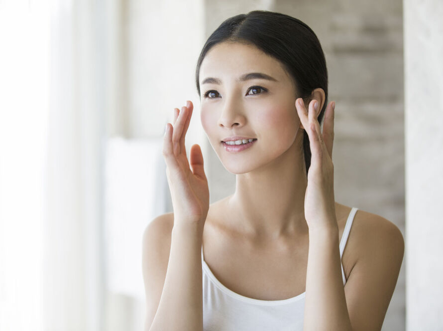Young woman applying moisturizer image